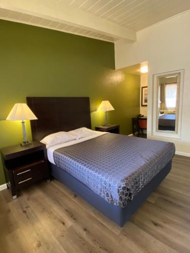 a bedroom with a bed and a green wall at Holiday Motel in Morgan Hill