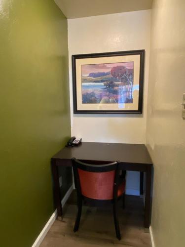 a desk with a chair and a painting on the wall at Holiday Motel in Morgan Hill