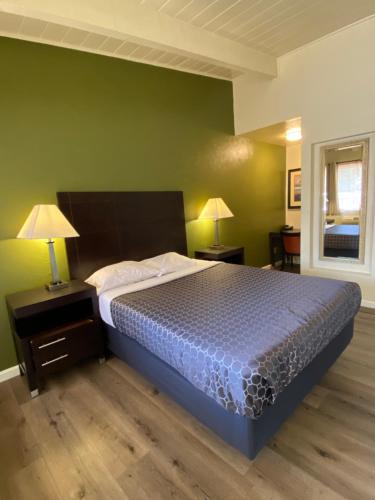 a bedroom with a bed and two lamps and a window at Holiday Motel in Morgan Hill