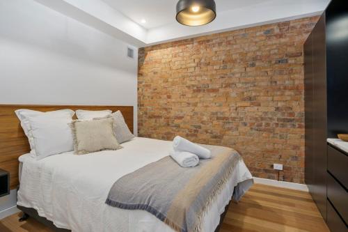 a bedroom with a brick wall and a bed at Saddlers House - Vintage Suite - Cafe Lifestyle in Hobart