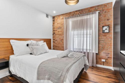 ein Schlafzimmer mit einem großen Bett mit Ziegelwand in der Unterkunft Saddlers House - City View - Cafe Lifestyle in Hobart
