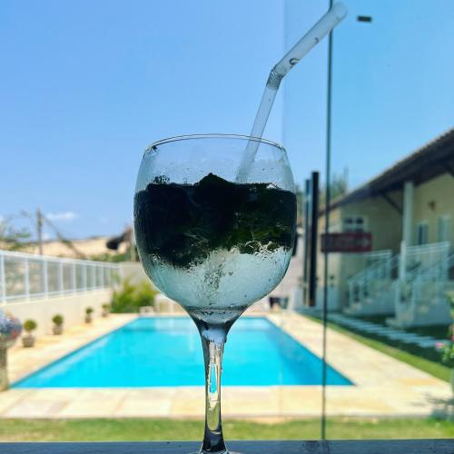 a glass of wine sitting on a table next to a pool at Villa do Nino in Canoa Quebrada