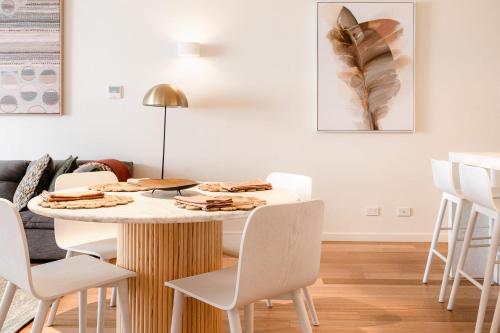 ein Esszimmer mit einem Tisch und weißen Stühlen in der Unterkunft The Rox - Luxe Hobart City Apartment in Hobart