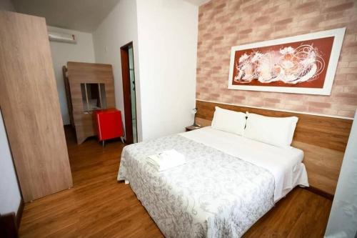 a bedroom with a white bed and a brick wall at Hotel Pousada Villas do Atlântico in Lauro de Freitas