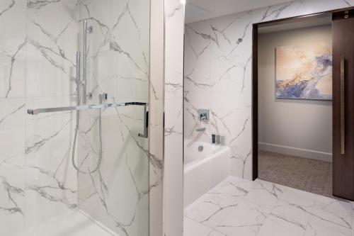 y baño con ducha y paredes de mármol blanco. en JW Marriott Miami en Miami