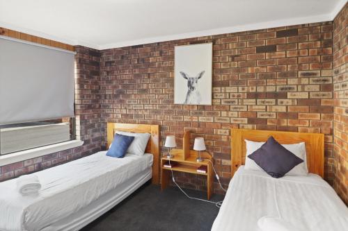 two beds in a room with a brick wall at Kellraine Holiday Units in St Helens