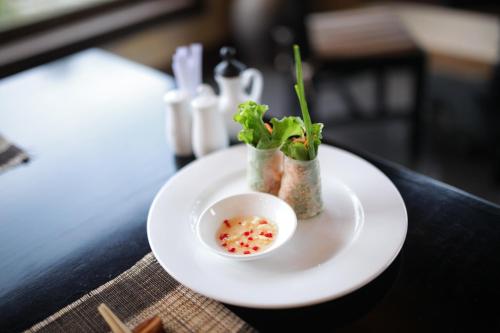 a white plate with a bowl of food on a table at Goda Boutique Hotel in Hoi An