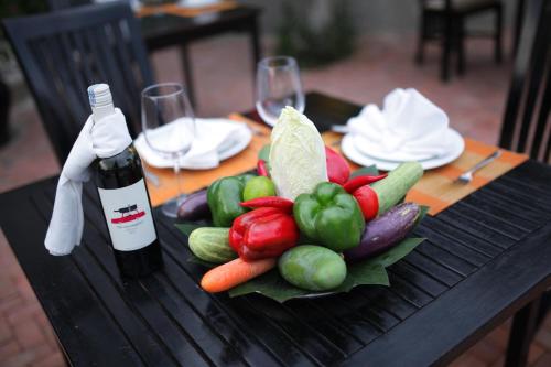 a plate of vegetables on a table with a bottle of wine at Goda Boutique Hotel in Hoi An