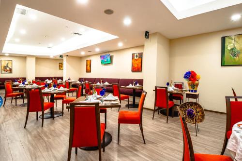 a dining room with tables and red chairs at Camino Real Aeropuerto in Mexico City