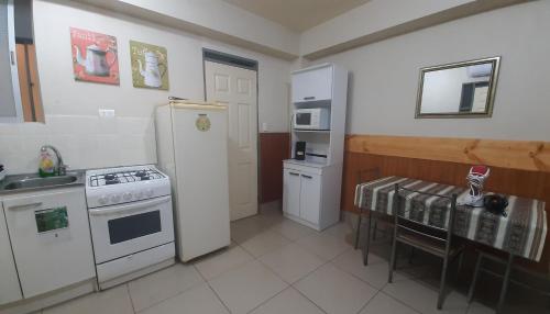 uma cozinha com um fogão, um frigorífico e uma mesa em Apart Maxi em Arica