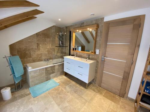 a bathroom with a sink and a tub and a mirror at Gîte spacieux 10 pers à Vagney - Sauna, jeux, proche Gérardmer - FR-1-589-400 in Vagney