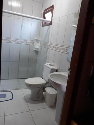 a white bathroom with a toilet and a sink at Chalé da Val in Palhoça