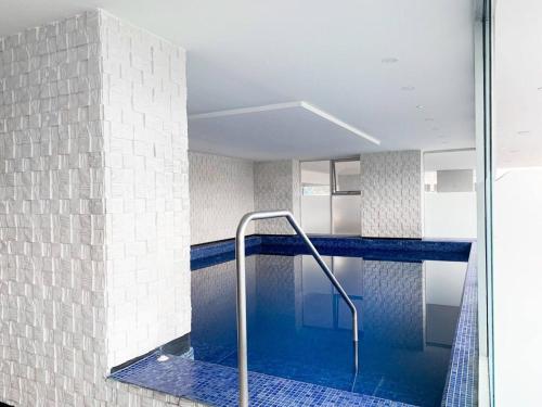 a swimming pool with blue tiles and a glass wall at Lujoso depa con vista a todo Guayaquil! in Guayaquil