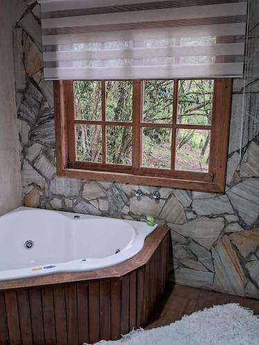 a bath tub in a bathroom with a window at Chalé dois irmãos in Visconde De Maua