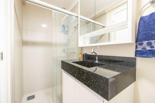 a bathroom with a sink and a glass shower at QUARTO privativo para 1 pessoa em Home Club in Balneário Camboriú