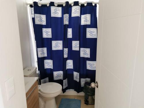 a bathroom with a toilet and a blue shower curtain at Lomas 5 in Papudo