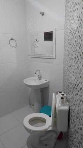 a white bathroom with a toilet and a sink at Residencial Maria de Lourdes in Ibicoara