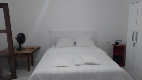 a bedroom with a white bed with two towels on it at Residencial Maria de Lourdes in Ibicoara