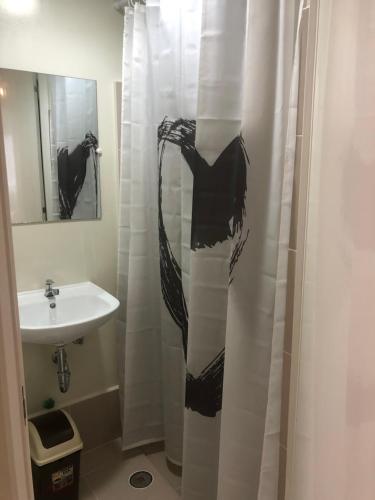 a bathroom with a black and white shower curtain and a sink at Brenthill Premium Condo Baguio City with Generator in Baguio