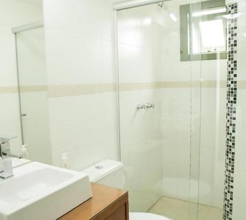 een badkamer met een douche, een toilet en een wastafel bij Apartamento Tomasini in Gramado