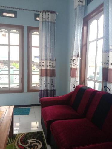 ein Wohnzimmer mit einem roten Sofa und Fenstern in der Unterkunft Dedwa Homestay syariah in Batu