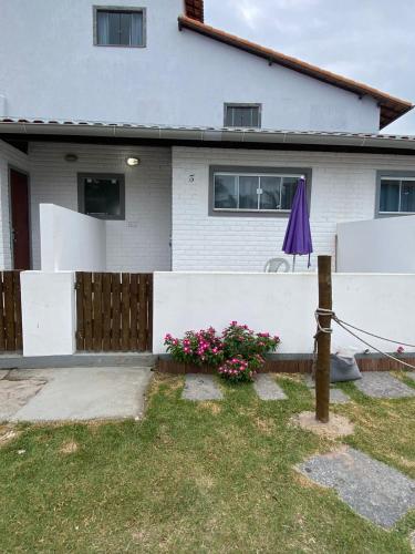 a house with a fence and a purple umbrella at Casa do Point in Saquarema