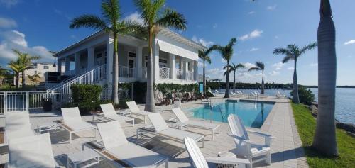una casa con sillas blancas y piscina en Oceans Edge Clubhouse, en Cayo Largo
