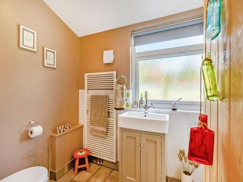 ein Bad mit einem Waschbecken und einem Fenster in der Unterkunft Holly Cottage in Clearwell