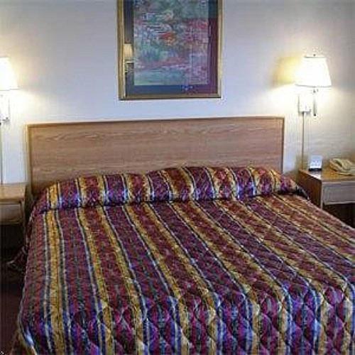 Habitación de hotel con cama con edredón colorido en Red Carpet Inn Starke, en Starke