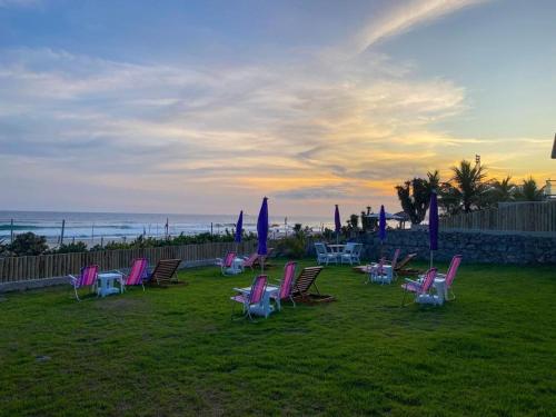 a group of chairs and tables with umbrellas on the beach at Casa do Point in Saquarema