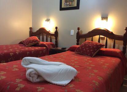 a bedroom with two beds with red sheets at Apart Hotel La Recova in Termas de Río Hondo