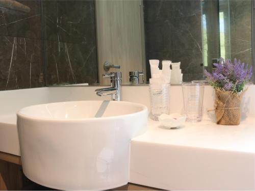 uma casa de banho com um lavatório branco e um espelho. em Aqueen Prestige Hotel Jalan Besar em Singapura