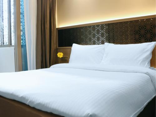 ein großes Bett mit weißer Bettwäsche und Kissen in der Unterkunft Aqueen Prestige Hotel Jalan Besar in Singapur