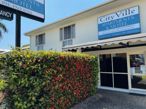 a sign for a city ville apartment building with a hedge at City Ville Apartments and Motel in Rockhampton