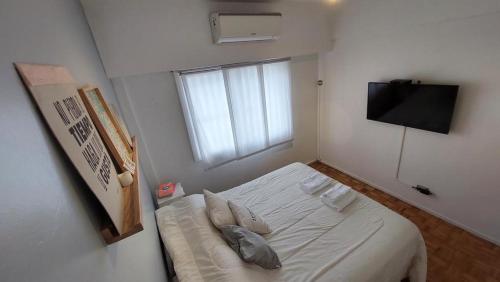 Cette petite chambre blanche comprend un lit et une télévision. dans l'établissement V&A, à Buenos Aires