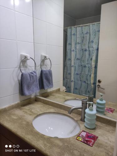 lavabo con espejo y cortina de ducha azul en HABITACION CON BAÑO PRIVADO, Depto HOME ESTUDIOS Gran Santiago Apartments, en Santiago