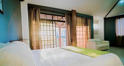 a bedroom with a white bed and a chair at HOTEL MANTA BEACH MADRIGAL in Manta