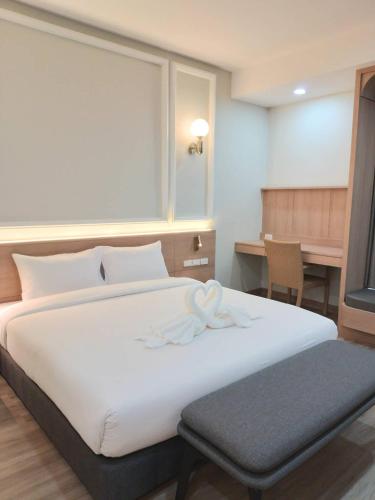 a bedroom with a large white bed and a desk at Mayflower Grande Suite Hotel in Phitsanulok
