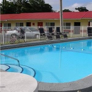 a large blue swimming pool in front of a hotel at Red Carpet Inn Starke in Starke