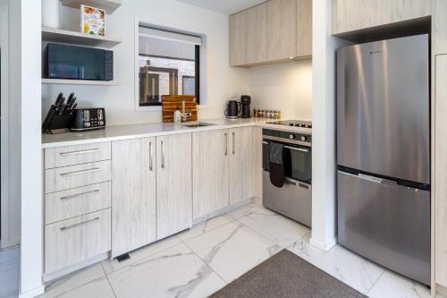 eine Küche mit Holzschränken und einem Kühlschrank aus Edelstahl in der Unterkunft Enchanted Escape 2 bed 2 bath CBD in Christchurch