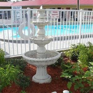 a white fountain in front of a swimming pool at Red Carpet Inn Starke in Starke
