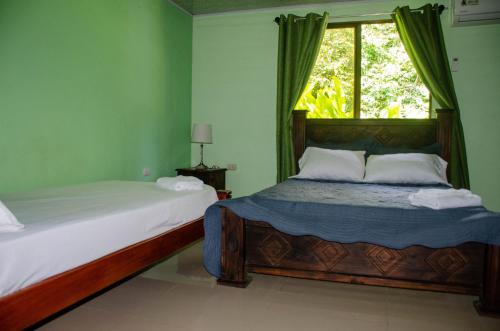 1 dormitorio con 2 camas y ventana en Natural Harmony Cabin, en Puerto Jiménez