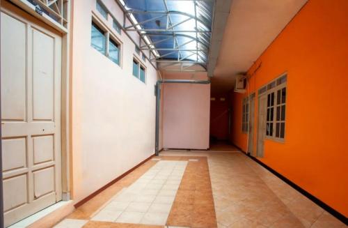 een lege hal met oranje muren en een deur bij Homestay at Homy House by ecommerceloka in Jomblang