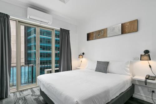 Comfort Hotel Melbourne Central في ملبورن: غرفة نوم بسرير ابيض ونافذة كبيرة