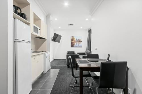 a kitchen and dining room with a table and chairs at Comfort Apartments Melbourne Central in Melbourne