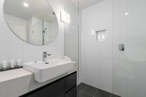 Baño blanco con lavabo y espejo en Comfort Hotel Melbourne Central, en Melbourne
