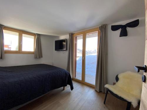 a bedroom with a bed and a window and a chair at Chalet rénové pour 12 pers., à 100m des pistes, 300m des commerces, terrasses et parking inclus - FR-1-733-146 in Crest-Voland