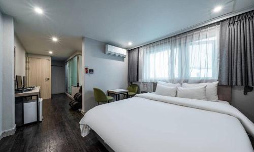 a hotel room with a large white bed and a desk at Anyang ILLOWA Hotel in Anyang