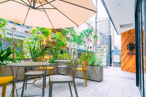 an outdoor seating area with tables and chairs and an umbrella at R Hotel Honmachi in Osaka