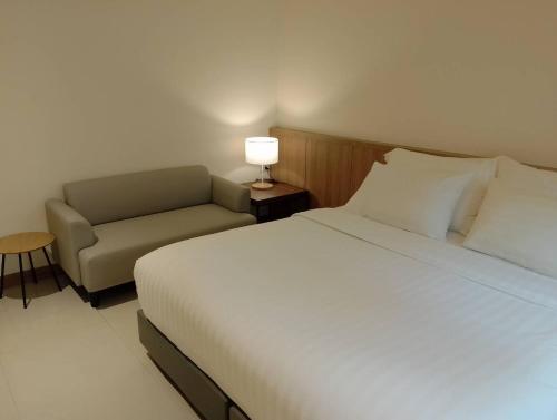 a bedroom with a bed and a chair and a lamp at Westerly Hill Pattaya in Pattaya Central